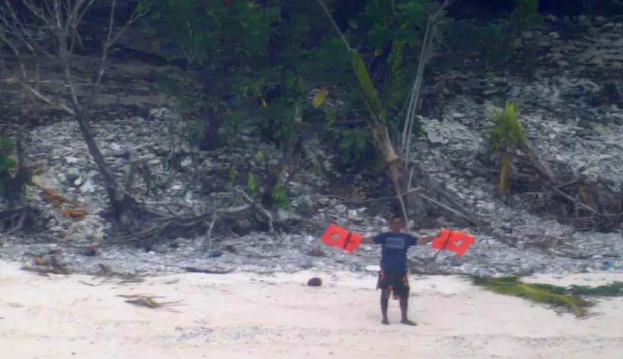 Seorang pria melambaikan jaket penyelamat saat meminta pertolongan ketika terdampar di Pulau Faradik, Mikronesia, 7 April 2016. Tiga orang pelaut terdampar setelah kapal yang mereka tumpangi tersapu ombak setinggi dua meter. (ENSIGN JOHN KNIGHT/NMCO/AFP)