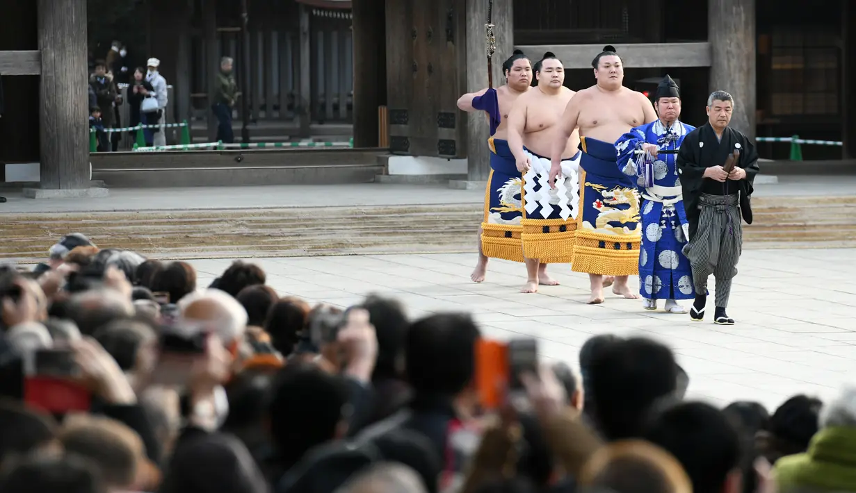 Juara Grand Sumo, Kakuryu (keempat kanan) tiba untuk melakukan upacara mengentakkan kaki menyambut tahun baru di Kuil Meiji, Tokyo, 8 Januari 2019. Ritual penyambutan tahun baru itu melibatkan tiga juara pegulat sumo. (Toshifumi KITAMURA/AFP)