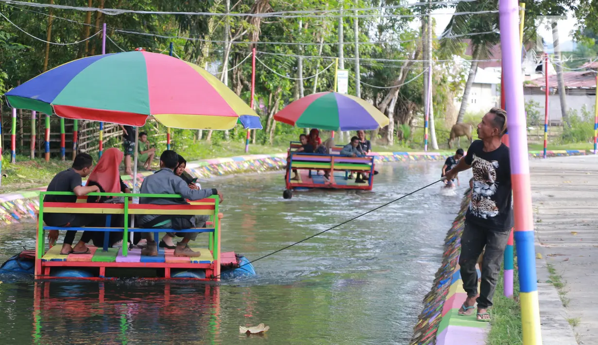 Wisatawan menaiki perahu apung di Wisata Air Toino, Desa Talulobutu, Kecamatan Tapa, Kabupaten Bone Bolango, Gorontalo, Sabtu (30/3). Warga sekitar menyulap drainase ini menjadi tempat wisata yang unik. (Liputan6.com/Arfandi Ibrahim)