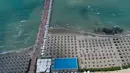 Foto udara pada 1 Juni 2020 menunjukkan payung-payung jerami di sebuah pantai di Qerret, dekat kota Kavaja, Albania. Rencananya pada 6 Juni mendatang, semua pantai umum akan dibuka untuk wisatawan setelah Albania menerapkan langkah-langkah pelonggaran pencegahan virus corona. (SHKULLAKU / AFP)