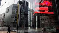 Sebuah jalan tercermin di gedung perkantoran yang memuat papan kutipan elektronik yang menampilkan angka-angka Indeks Nikkei 225 di Bursa Efek Tokyo di Tokyo pada 10 Maret 2022.Behrouz MEHRI / AFP
