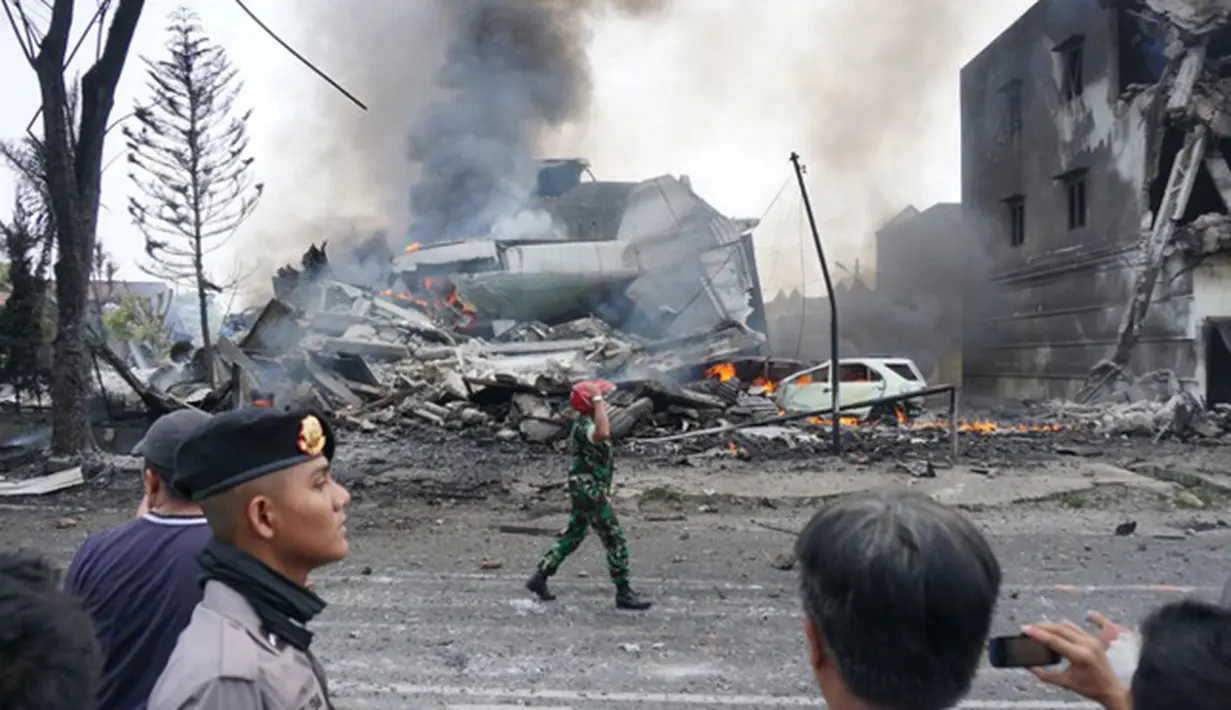 Petugas saat mengamankan lokasia kecelakaan pesawat Hercules C-130 yang jatuh di kawasan perumahan di Medan, Selasa (30/6/2015). Hercules C-130 milik TNI AU jatuh tidak lama setelah lepas landas. (AFP PHOTO/Muhammad Zulfan Dalimunthe)