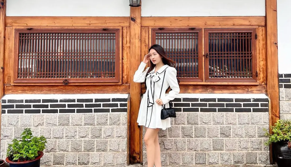 Seperti saat berkunjung ke kampung wisata Hanok ini. Aktris 23 tahun itu tampil manis pakai mini dress putih dengan aksen pita, dipadukan dengan sneakers dan sling bag. (Instagram/natashawilona12).