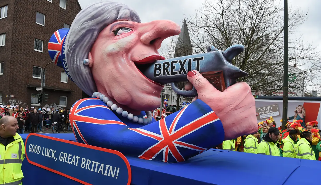 Patung menyerupai PM Inggris Theresa May dengan pistol bertulisan "Brexit" ikut dalam karnaval tradisional 'Rose Monday' di Dusseldorf, Jerman, Senin (27/2). Karnaval 'Rose Monday' berisi sindiran satir para pemimpin dunia. (AFP PHOTO / Patrik STOLLARZ)