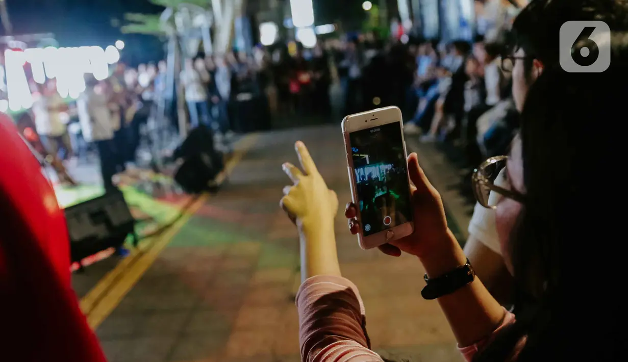 Pejalan kaki menikmati acara bertajuk Musik Tepi Barat dan Timur di jalur pedestrian kawasan Sudirman, Jakarta, Jumat (22/11/2019). Acara musik yang rutin digelar itu bertujuan untuk menghibur para pejalan kaki dan pekerja kantoran yang beraktivitas di kawasan tersebut. (Liputan6.com/Faizal Fanani)