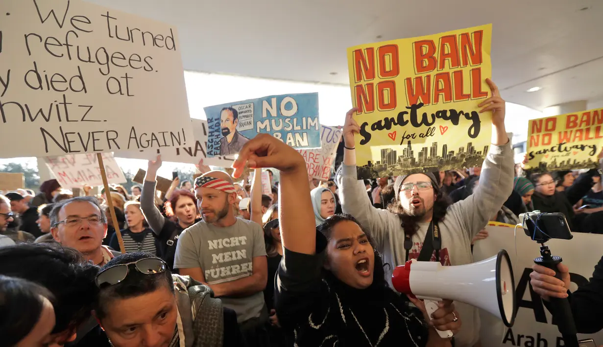 Pengunjuk rasa berorasi saat menggelar aksi protes di Bandara Internasional San Francisco, Sabtu (28/1). Mereka memprotes kebijakan Presiden AS, Donald Trump yang melarang warga dari 7 negara muslim masuk Amerika Serikat. (AP Photo/Marcio Jose Sanchez)