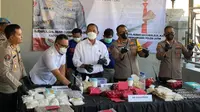 Polda Jatim mengamankan dua tersangka kasus pabrik rumahan ektasi dan pil koplo di Surabaya. (Dian Kurniawan/Liputan6.com)
