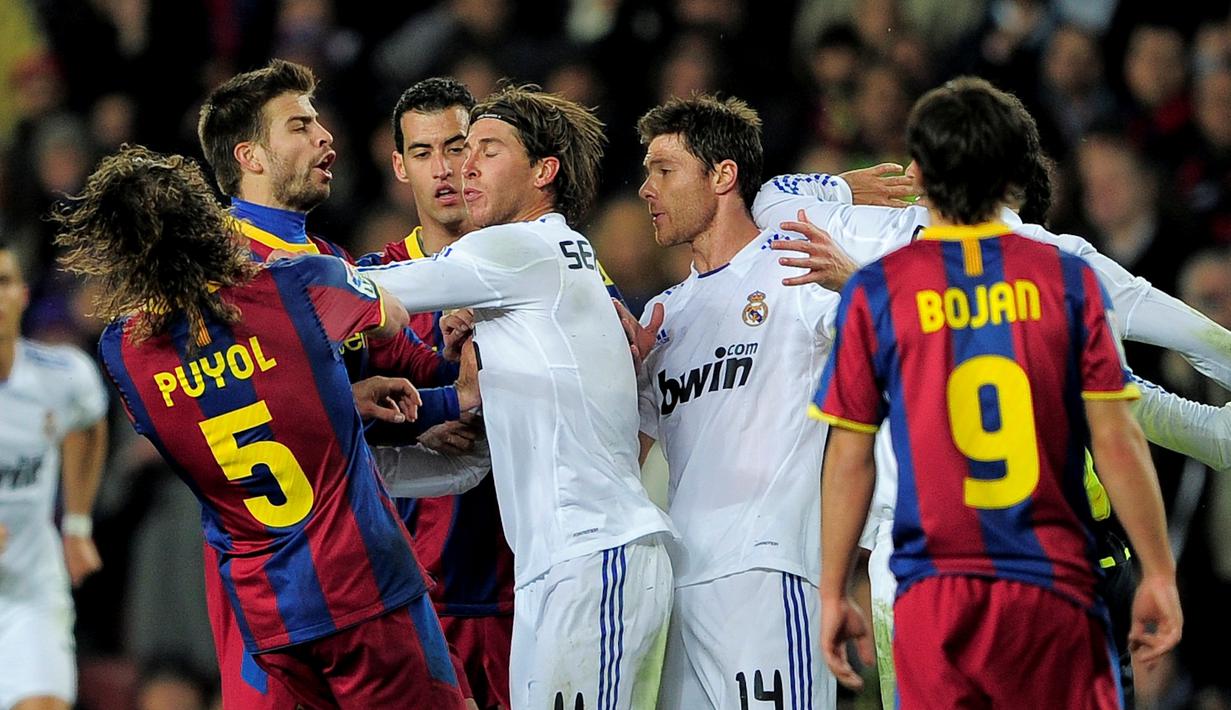 Pemain Madrid, Sergio Ramos, mendorong Carles Puyol hingga terjatuh saat Puyol memprotes Ramos karena melanggar keras Messi. Barcelona menang 5-0 dalam laga di Stadion Camp Nou, Barcelona, (29/11/2010). (AFP Photo/Josep Lago)