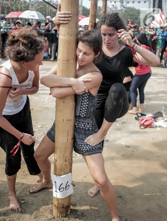 Sejumlah warga negara asing mengikuti panjat pinang kolosal dalam rangka merayakan HUT ke-74 Kemerdekaan RI di Pantai Karnaval, Ancol, Jakarta, Senin (17/8/2019). Sebanyak 174 batang pinang dengan beragam hadiah disediakan dalam lomba yang diikuti ratusan warga itu. (Liputan6.com/Faizal Fanani)