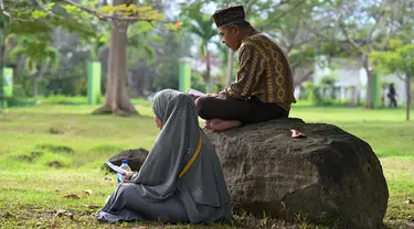 Orang-orang berdoa saat memperingati 18 tahun musibah gempa dan tsunami di kuburan massal Siron, Aceh, Senin (26/12/2022). Sejumlah warga mendatangi Kuburan Massal Siron untuk memenjatkan doa saat peringatan 18 tahun musibah gempa dan tsunami Aceh 2004. (AFP/Chaideer Mahyuddin)