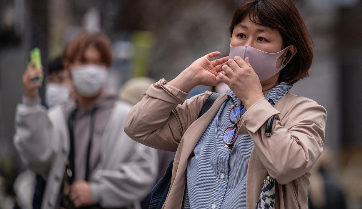 Orang-orang menyeberang jalan di distrik Shibuya Tokyo pada hari pertama pemerintah Jepang mencabut ketentuan wajib mengenakan masker, Senin (13/3/2023). Sebelumnya selama tiga tahun terakhir Jepang mewajibkan pemaikaian masker akibat pandemi Covid-19. (Photo by Yuichi YAMAZAKI / AFP)