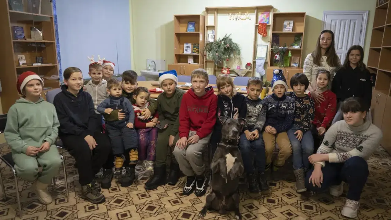 Anak-anak korban trauma perang Ukraina berfoto dengan American Pit Bull Terrier "Bice" di Pusat Rehabilitasi Sosial dan Psikologis di Boyarka, Ukraina, Rabu, 7 Desember 2022. (Vasilisa Stepanenko/AP Photo)