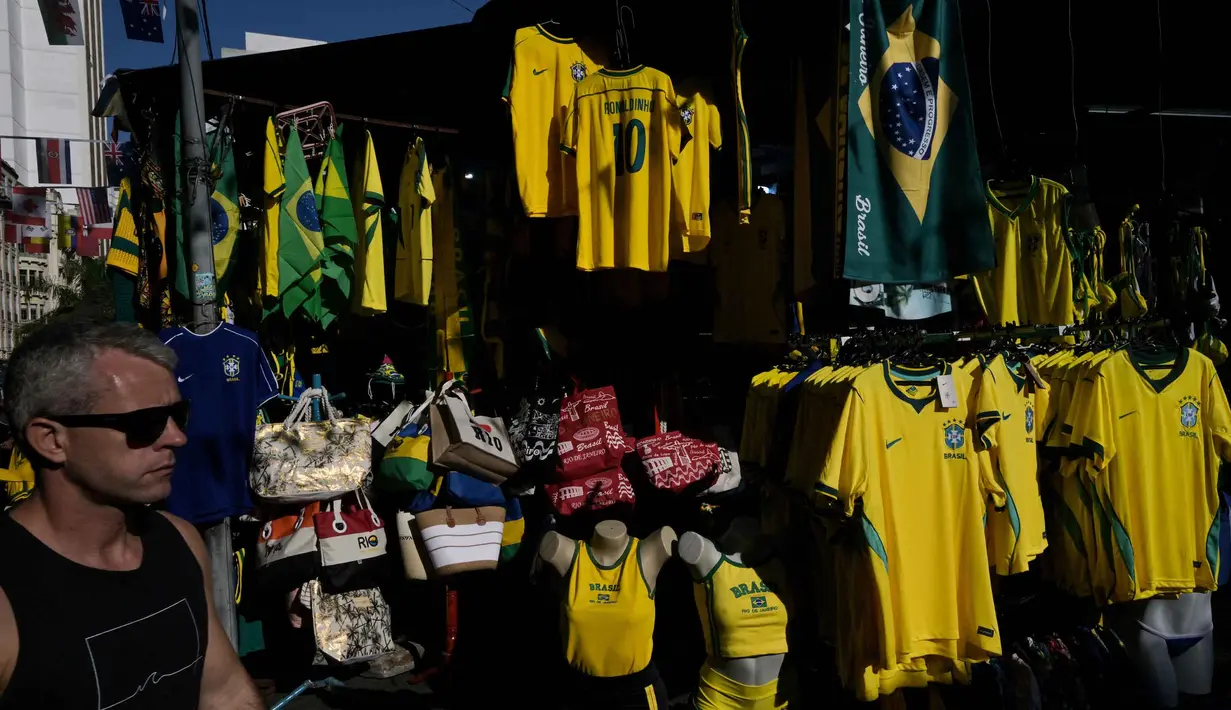Seorang pria berjalan melewati kaus tim sepak bola nasional Brasil yang dipajang di pasar Saara, Rio de Janeiro, Brasil, pada Selasa 9 Juni 2026, menjelang turnamen Piala Dunia FIFA 2026. (Nelson ALMEIDA/AFP)