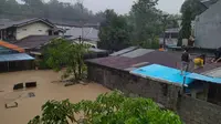 Sejumlah warga Manado memilih naik ke atap rumah karena volume air yang terus meningkat akibat banjir.