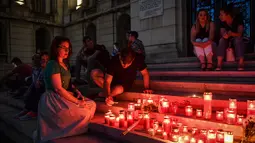 Warga menyalakan lilin untuk memperingati gadis berusia 15 tahun Alexandra yang terbunuh di depan Kementerian Dalam Negeri Rumania di Bucharest (27/7/2019). Kepala polisi Rumania telah dipecat setelah pembunuhan Alexandra yang menelepon tiga kali. (AFP Photo/Daniel Mihailescu)