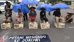 Sambil menggunakan payung, Petani Kendeng menyemen kaki saat menggelar aksinya di depan Istana Negara, Jakarta, Selasa (14 /3). Aksi ini sebagai bentuk penolakan terhadap Keputusan Gubernur Jawa Tengah Nomor 660.1/6 Tahun 2017. (Liputan6.com/Helmi Afandi)
