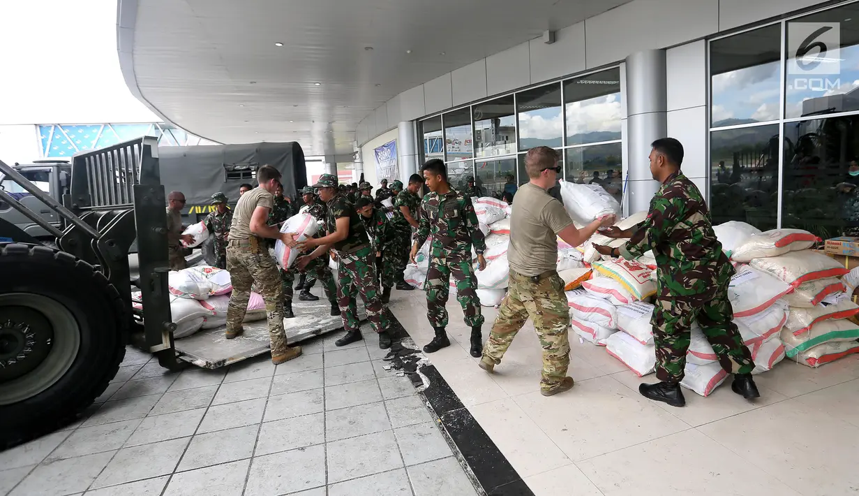 Prajurit TNI dibantu tentara Amerika Serikat mendistribusikan bantuan logistik yang tiba di Bandara Mutiara Sis Al-Jufri, Palu, Sulawesi Tengah, Minggu (7/10). Bantuan asing tiba menggunakan pesawat Hercules. (Liputan6.com/Fery Pradolo)