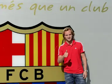 Gelandang asal Kroasia Ivan Rakitic berfoto di depan logo Barcelona di depan kantor klub, Spanyol, Senin (30/6/14). (AFP PHOTO/Josep Lago)