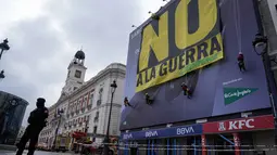 Di salah satu bangunan Lapangan Puerta del Sol, Madrid, Spanyol, pada Selasa 10 Maret 2026, sejumlah aktivis Greenpeace membentangkan spanduk besar bertuliskan "Tidak untuk Perang". Tampak dalam foto, petugas polisi membentuk perimeter saat aktivis Greenpeace membentangkan spanduk besar bertuliskan "Tidak untuk Perang" sebagai bentuk protes terhadap serangan Amerika Serikat (AS) dan Israel terhadap Iran, di Lapangan Puerta del Sol, Madrid, Spanyol, pada Selasa 10 Maret 2026. (Paul Hanna/AFP)