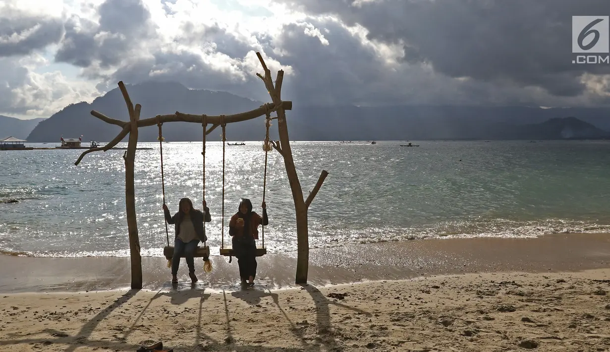 Dua wanita bermain ayunan saat menikmati Pantai Mutiara di Trenggalek, Jawa Timur, Sabtu (7/9/2019). Pantai Mutiara salah satu tujuan wisata yang sedang dikembangkan kabupaten Trenggalek. (Liputan6.com/Herman Zakharia)