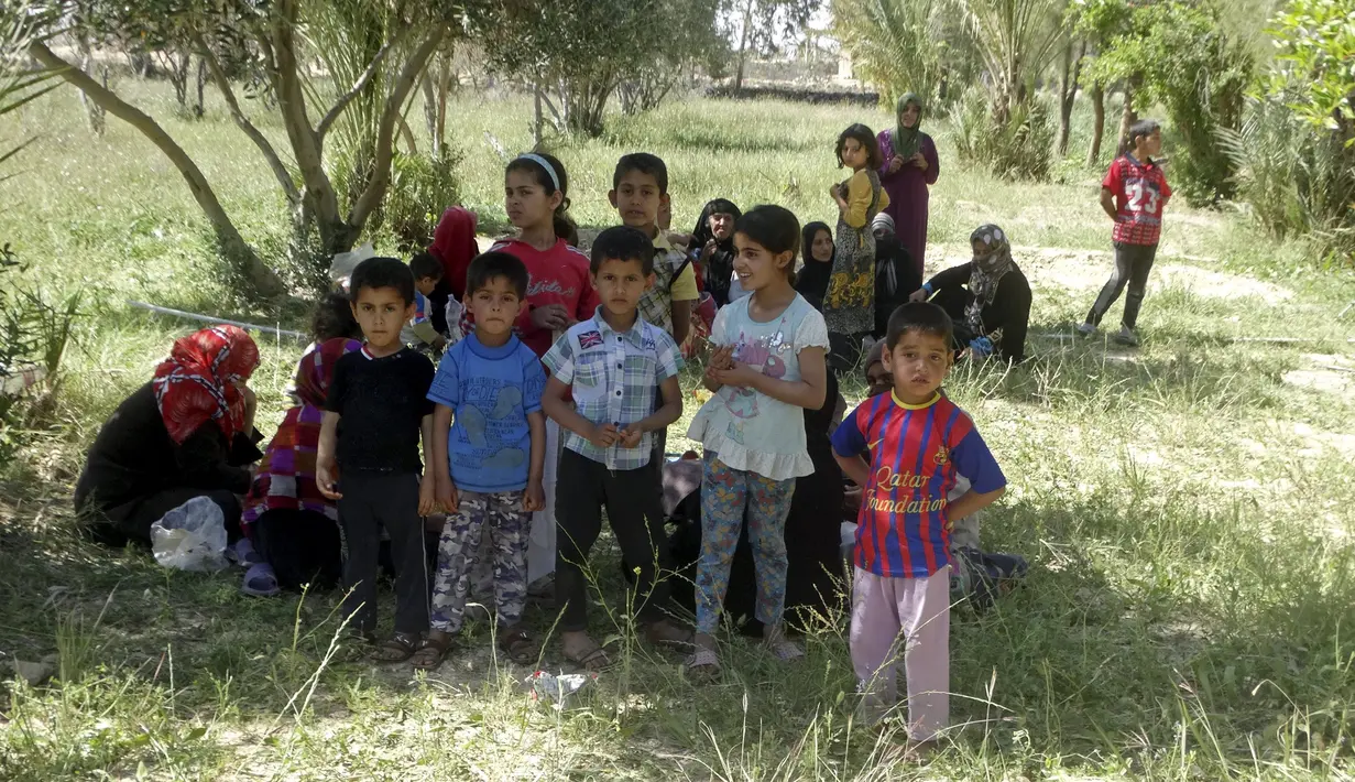 Sejumlah anak-anak beristirahat dibawah pohon setelah berjalan ketika melarikan diri akibat pertempuran antara pasukan Irak dan militas ISIS di kota Hit, provinsi Anbar, (5/4/2016). (REUTERS/Stringer)