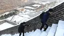 Dua wisatawan menaiki anak tangga saat menikmati liburan musim dingin di Tembok Besar China yang diselimuti salju di utara Beijing (6/1/2020). Salju yang turun tidak menyurutkan para wisatawan baik lokal maupun dari mancanegara untuk berkunjung ke Tembok Besar China. (AFP/Greg Baker)