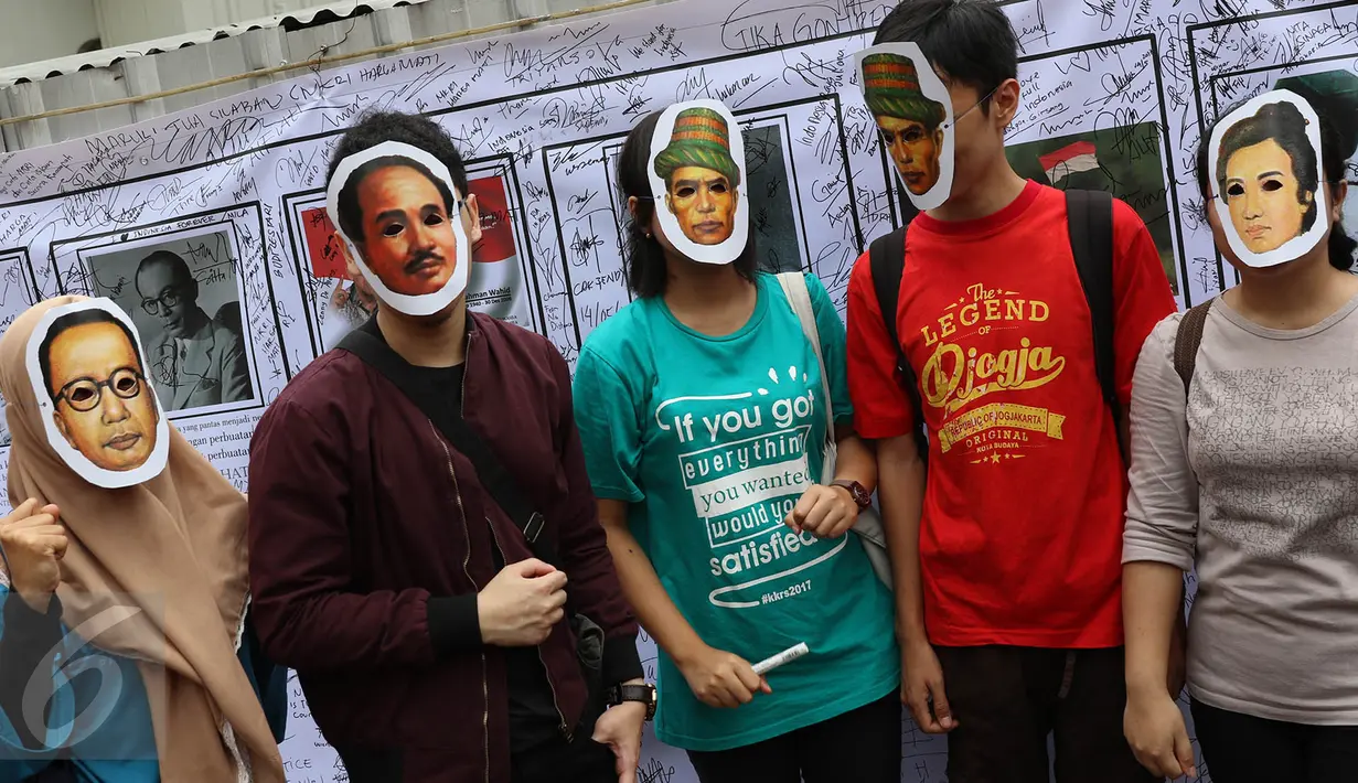 Warga berfoto bersama mengenakan topeng bergambar pahlawan nasional di depan spanduk yang penuh tanda tangan di area car free day, Jakarta, Minggu (14/5). (Liputan6.com/Immanuel Antonius)