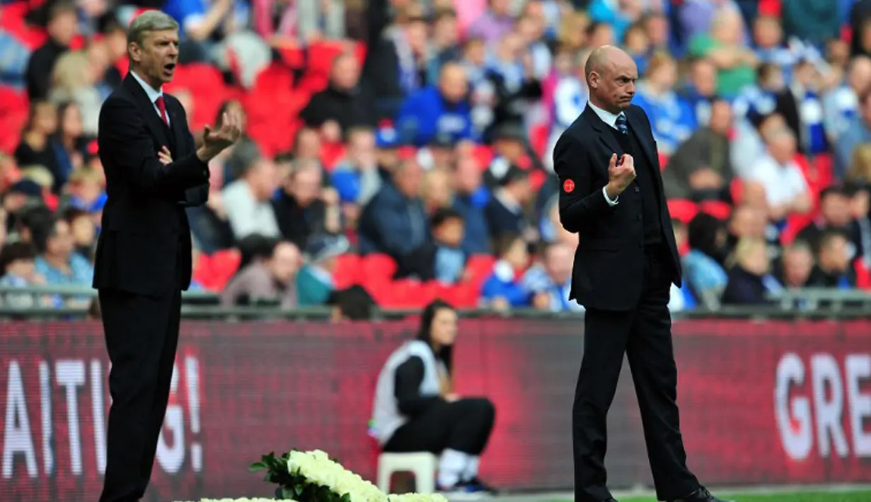 Manajer Wigan Athletic Uwe Rosler (kanan) dan Arsene Wenger saling memberikan arahan pada pemainnya selama pertandingan semifinal Piala FA di Stadion Wembley, London (12/4/2014). (AFP PHOTO/Glyn Kirk)