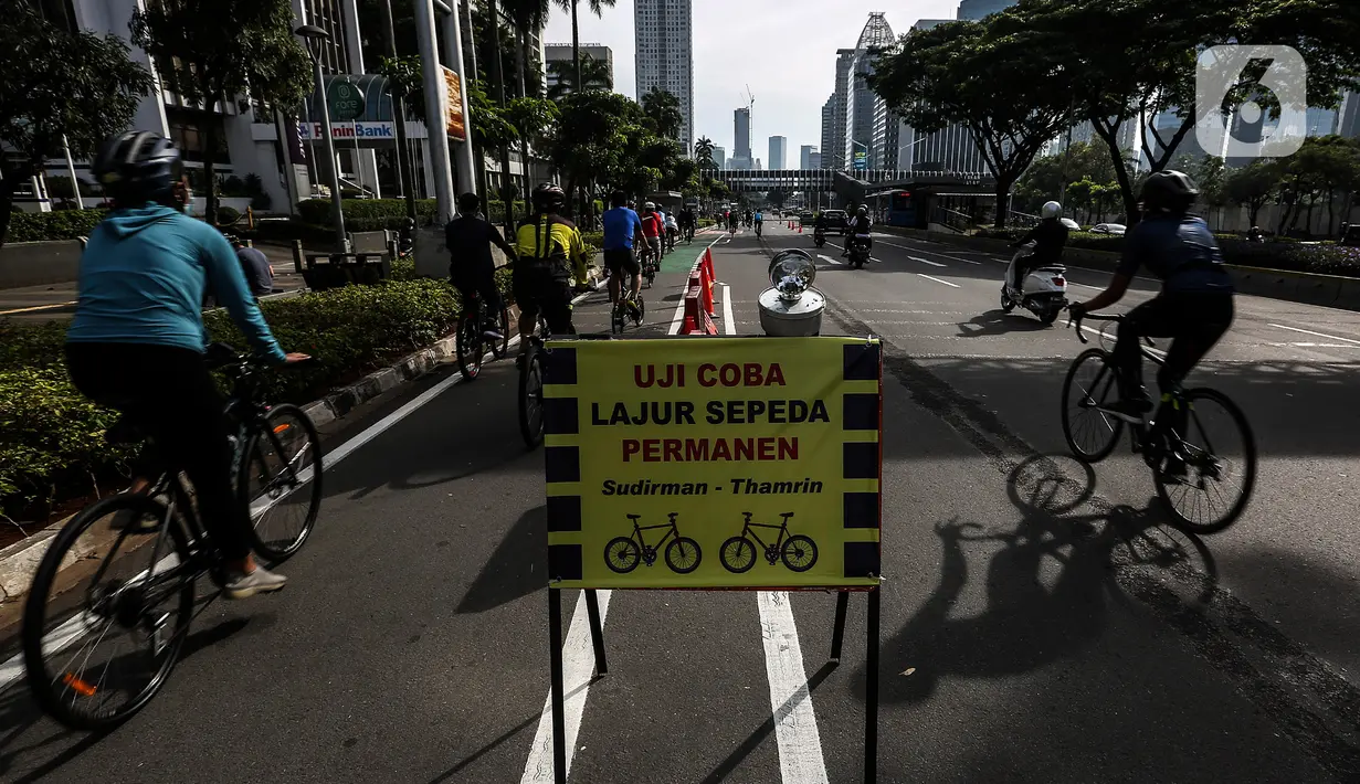 Papan pengumuman uji coba pembatas jalur sepeda permanen terlihat di kawasan Sudirman, Jakarta, Minggu (28/2/2021). Uji coba berlangsung selama tahap penyempurnaan jalur sepeda permanen yang ditargetkan rampung akhir Maret 2021. (Liputan6.com/Johan Tallo)