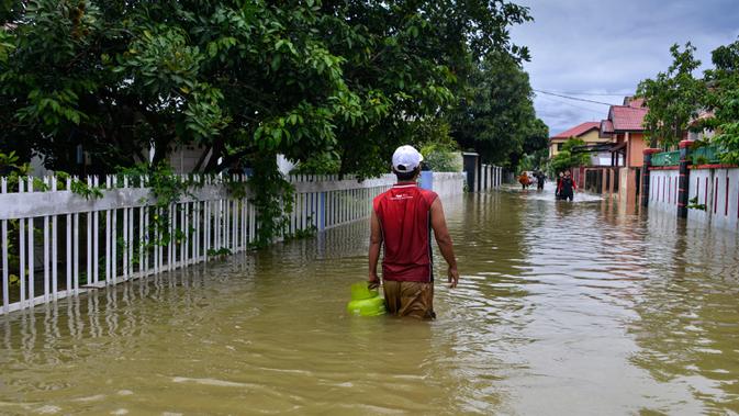 Seorang pria menerebos banjir setelah tiga hari diguyur hujan lebat di Banda Aceh, Aceh, Sabtu (9/5/2020). Banjir akibat intensitas hujan tinggi tersebut mengakibatkan sebagian besar kawasan di ibu kota Provinsi Aceh ini digenangi air. (Photo by CHAIDEER MAHYUDDIN/AFP)