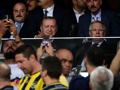 Presiden Turki Recep Tayyip Erdogan (tengah) tersenyum kepada penonton saat menyaksikan pertandingan putaran ketiga kualifikasi UEFA Europa League antara Fenerbahce dan Sturm Graz di Stadion Ulker Fenerbahce di Istanbul (3/8). (AFP Photo/Ozan Kose)