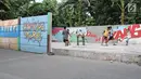 Anak-anak bermain bola di sisi tembok yang terdapat lukisan mural di kawasan Kramat Jati, Jakarta, Rabu (4/4). Kawasan ini mendapat julukan Kampung Mural. (Liputan6.com/Herman Zakharia)