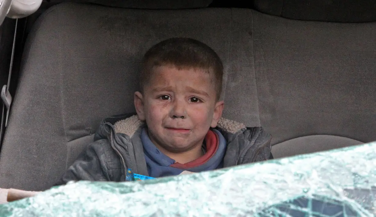 Seorang bocah menangis saat dievakuasi setelah serangan udara rezim di Kota Ariha, Idlib, Suriah, Rabu (15/1/2020). Sebanyak sembilan orang dilaporkan tewas dalam serangan pasukan pemerintah terhadap benteng terakhir oposisi tersebut. (Abdulaziz KETAZ/AFP)