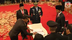 Komjen Pol Idham Azis (kiri) menandatangani berkas disaksikan Presiden Joko Widodo (kanan), Menteri Dalam Negeri Tito Karnavian (kedua kiri), Panglima TNI Hadi Tjahjanto (kedua kanan) saat upacara pelantikannya sebagai Kapolri di Istana Negara, Jakarta, Jumat (1/11/2019). (Liputan6.com/Angga Yuniar)