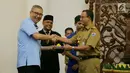 Gubernur DKI Jakarta Anies Baswedan (kanan) menyerahkan nasi tumpeng kepada Dirut PT Transjakarta Budi Kaliwono, Jakarta, Selasa (20/3). Menurut Anies, Transjakarta harus bisa menjadi model pengelolaan transportasi massal. (Liputan6.com/Pool/Dadang WS)