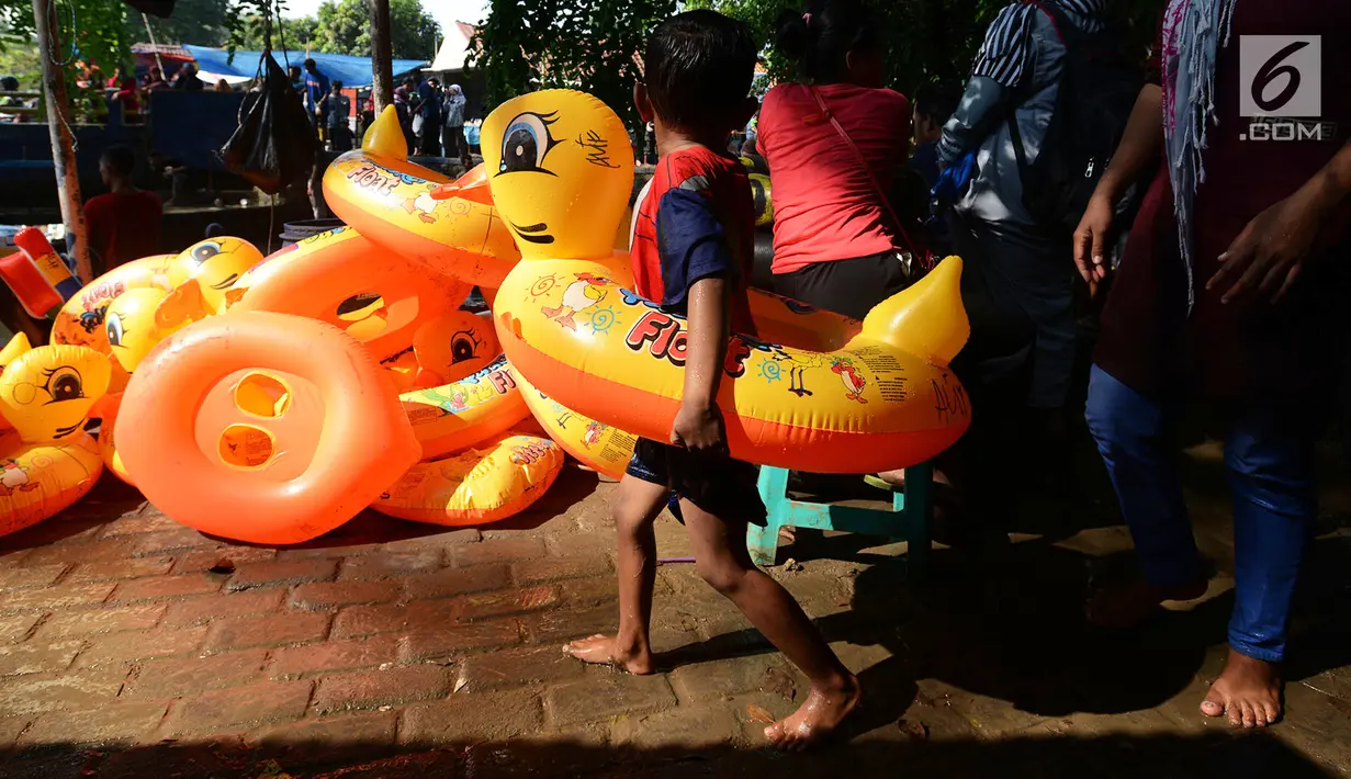 Seorang anak membawa pelampung bebek untuk bermain air di wisata alam Mata Air Sodong di Desa Ligar Mukti, Klapanunggal, Kabupaten Bogor, Jawa Barat, Minggu (9/6). Pengunjung hanya dikenakan Rp 10.000 untuk motor dan mobil Rp 20.000 di tempat wisata ini. (merdeka.com/Imam Buhori)