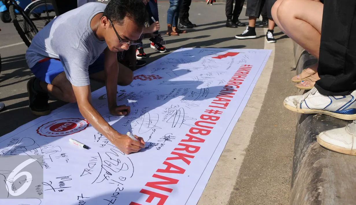 Seorang warga memberikan tanda tangan saat aksi dari Save NKRI di sekitar patung kuda di jalan Merdeka Barat, Jakarta, Minggu (8/1). Hal tersebut di karenakan mereka menilai FPI telah melakukan penghinaa terhadap pancasila. (Liputan6.com/Helmi Affandi)