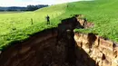 Warga melihat lubang besar yang muncul di peternakan sapi perah dekat Rotorua di Pulau Utara Selandia Baru (2/5). Seorang pekerja menemukan lubang tersebut sebelum fajar ketika mengumpulkan sapi untuk memerah susu. (AFP Phot/TVNZ)