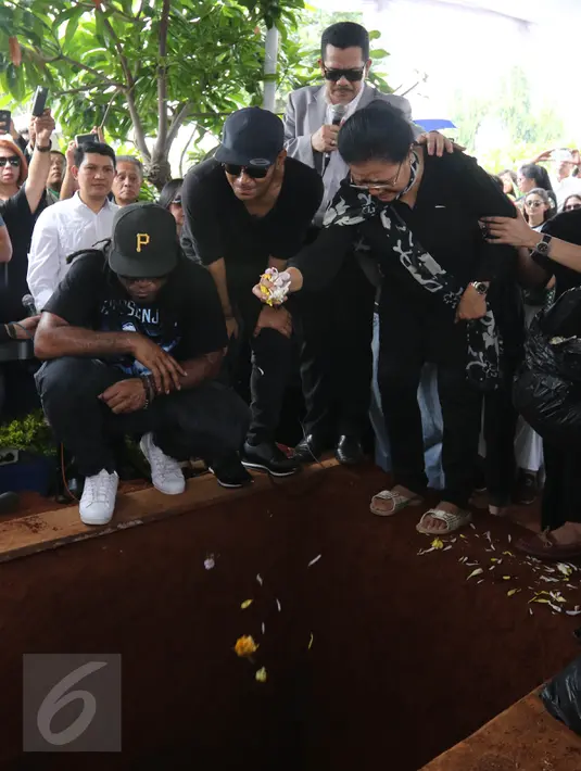 Ibunda Mike Mohede, Amin Yudhayani, menabur bunga ke dalam liang lahat putranya dalam prosesi pemakaman di TPU Tanah Kusir, Jakarta, Selasa (2/8). Prosesi pemakaman Mike Mohede berjalan diiringi isak tangis para pelayat. (Liputan6.com/Herman Zakharia)