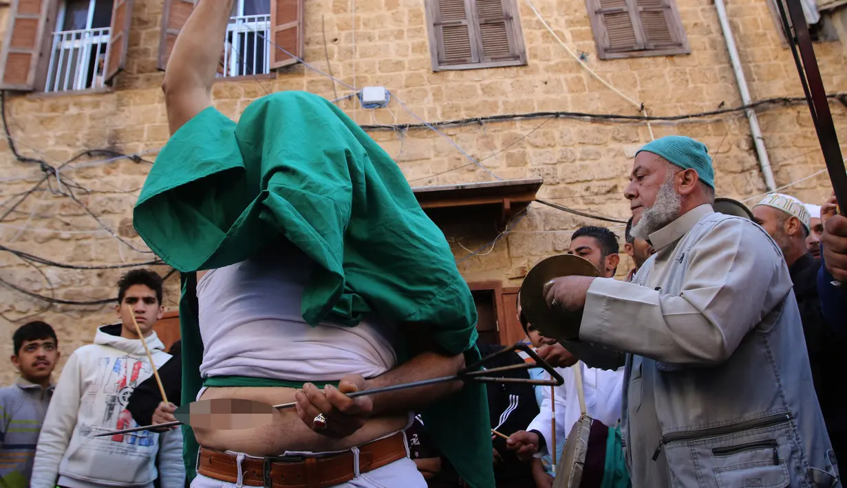 Warga muslim Sufi menusukkan benda tajam ke perutnya saat perayaan Maulid Nabi Muhammad SAW di Sidon, Lebanon (30/11). Tradisi yang mirip debus ini menjadi budaya kaum Sufi Lebanon saat memperingati Maulid Nabi. (AFP Photo/Mahmoud Zayyat)