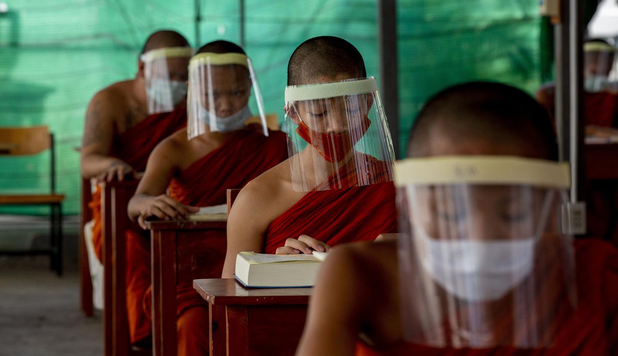 Para biksu muda mengenakan masker dan pelindung wajah saat belajar agama di Molilokayaram Educational Institute, Bangkok, Thailand, Rabu (15/4/2020). Sekitar 200 biksu muda tetap bersekolah kendati Thailand menutup semua sekolah selama lockdown akibat COVID-19. (AP Photo/Gemunu Amarasinghe)
