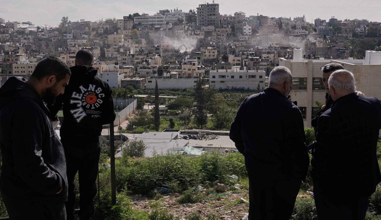 Untuk diketahui, Nur Shams didirikan ketika ratusan ribu warga Palestina mengungsi setelah berdirinya Israel pada tahun 1948. Sejak saat itu, kamp-kamp ini telah menjadi lingkungan padat penduduk, dengan para penghuninya mewariskan status pengungsi mereka dari generasi ke generasi. Tampak dalam foto, warga menyaksikan buldoser tentara Israel merobohkan rumah-rumah di kamp pengungsi perkotaan Palestina Nur Shams, dekat kota Tulkarem di Tepi Barat, Rabu 31 Desember 2025. (AP Photo/Majdi Mohammed)