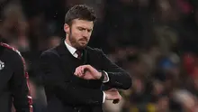 Hal itu disampaikan MU di laman resmi klub pada Rabu (14/1/2026) dini hari WIB. Tampak dalam foto, Michael Carrick saat masih menjadi pelatih sementara Manchester United melihat arlojinya selama pertandingan sepak bola Liga Premier Inggris melawan Arsenal di Old Trafford, Manchester, Inggris barat laut, pada 2 Desember 2021. (Oli SCARFF/AFP)