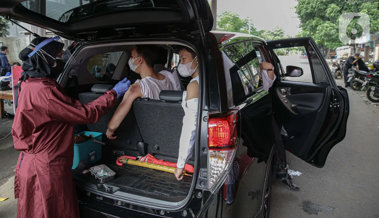 Petugas menyuntikkan vaksin COVID-19 kepada warga saat pelaksanaan vaksinasi secara drive-thru di Mapolres Jakarta Selatan, Selasa (29/6/2021). Layanan ini dilakukan untuk mempercepat vaksinasi COVID-19 kepada warga. (Liputan6.com/Faizal Fanani)
