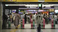 Seorang wanita yang mengenakan masker untuk membantu mengekang penyebaran virus corona COVID-19 keluar dari gerbang stasiun kereta api di Tokyo, Jepang, Jumat (6/8/2021). Tokyo dalam keadaan darurat virus corona COVID-19 sejak pertengahan Juli. (AP Photo/Kantaro Komiya)