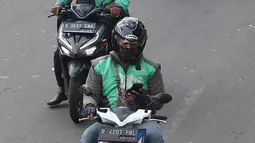 Pengendara sepeda motor mengoperasikan gawainya saat berkendara di Jakarta, Jumat (8/2). Menggunakan GPS saat berkendara dianggap melanggar UU Nomor 22 Tahun 2009 tentang Lalu Lintas dan Angkutan Jalan. (Liputan6.com/Immanuel Antonius)