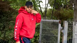 Pembalap Mercedes asal Inggris Lewis Hamilton berjalan di paddock sebelum Grand Prix Formula Satu China di Shanghai (12/4). Hamilton keren mengenakan kaca mata dan jaket berwarna merah. (AFP Photo/Johannes Eisele)