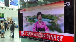 Warga menonton penyiar berita Korea Utara, Ri Chun-Hee menginformasikan berita tentang tes ICBM baru di stasiun kereta di Seoul pada 4 Juli 2017. Saat itu Korut memproklamirkanelah berhasil menguji rudal balistik antar benua. (AFP Photo/Jung Yeon-Je)