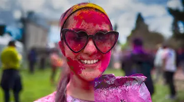Seorang wanita yang mengenakan kacamata hitam memoles wajahnya dengan bedak warna-warni saat merayakan Holi, festival warna Hindu, di bagian Encino, Los Angeles, Minggu, 24 Maret 2024. (AP Photo/Richard Vogel)