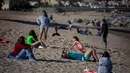 Orang-orang bersantai di pantai di Badalona, dekat Barcelona, Spanyol, Selasa, (28/4/2020). Lockdown untuk memerangi penyebaran virus corona terus berlanjut di Spanyol. (AP Photo/Emilio Morenatti)